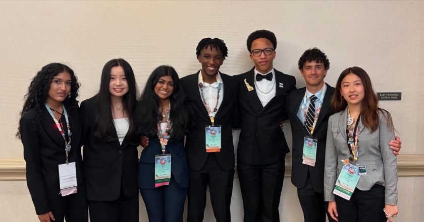 Seven students stand together, smiling at the camera.